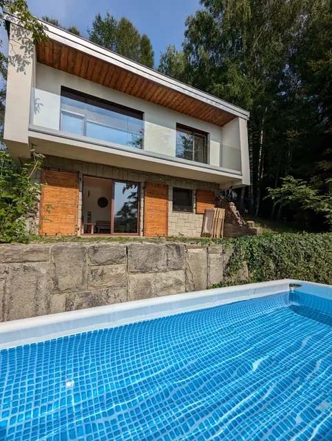 Willa z basenem w lesie oraz z widokiem na jezioro, góry i ruiny zamku.